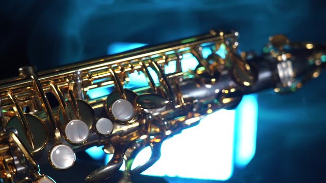 Golden shiny alto saxophone on black background with blue smoke