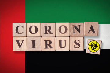 United Arab Emirates flag background and wooden blocks with letters spelling CORONAVIRUS and quarantine symbol on it. Novel Coronavirus (2019-nCoV) concept for an outbreak occurs in UAE.