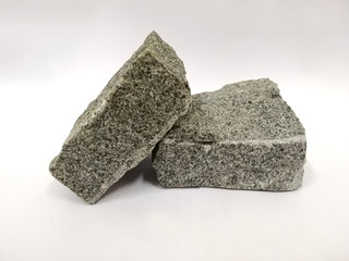 Gray granite cobble stone on white background. Granite is igneous rocks. There is noise and grain caused by the texture of the stone.