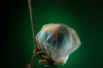 Globe in a cellophane bag in a loop of rope. The concept of ecology problems and World Environment Day.