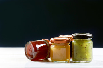 glass jar of homemade jam on wooden table and black background
