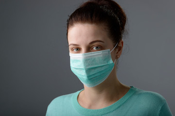 Portrait of female doctor or nurse wearing protective mask. Woman wearing face medical mask, looking at camera, isolated on gray background. Flu epidemic, dust allergy, protection against virus.