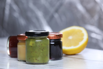 glass jar of kiwi jam, berry jam and honey, lemon on wooden table