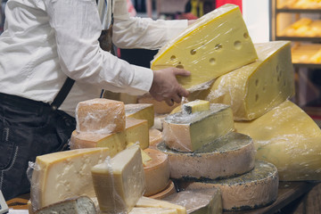 Man salesman in the shop with  cheese. Food