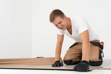 Male worker installing laminate flooring. Adult man lays the laminate panel on the substrate with the technology