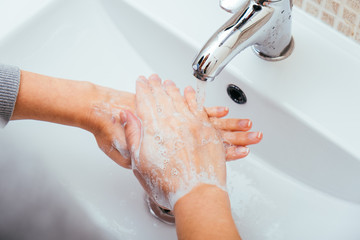 Woman Washing her hands with soap and water at home bathroom. Cleansing hand hygiene for coronavirus outbreak prevention. Corona Virus pandemic protection