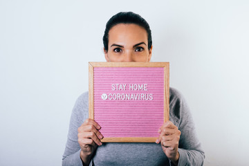 Woman holding sign in her hands with word stay home due to coronavirus