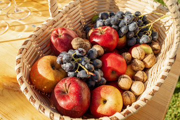 Autumn fruits in a basket. Fresh apples, nuts and grapes in autumn light
