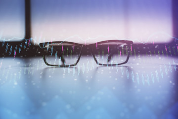 Financial graph hologram with glasses on the table background. Concept of business. Double exposure.