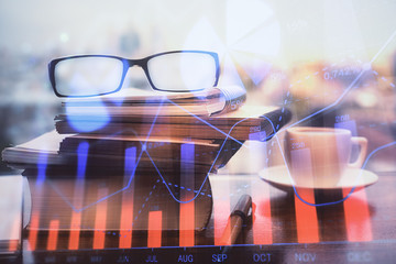 Financial graph hologram with glasses on the table background. Concept of business. Double exposure.