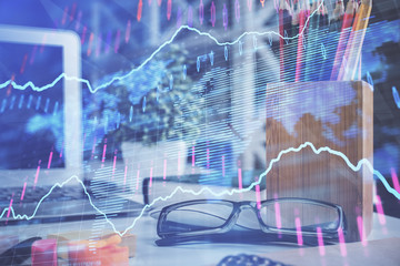 Financial chart hologram with glasses on the table background. Concept of business. Double exposure.