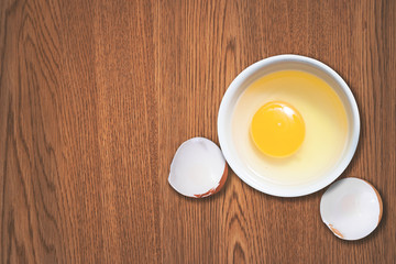 Top view of chicken egg yolk in a bowl on wood table. Copy space is provided.