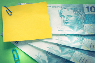 Fototapeta na wymiar Brazilian money, 100 reais banknotes on green background with blank yellow card for text