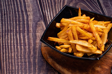 potatoes fries in black dish  wooden Board.