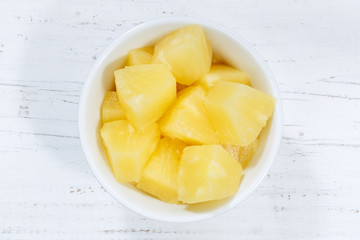 Pineapple slices fruits from above bowl on a wooden board