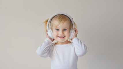 home, technology and music concept - little girl with headphones listening to music and singing