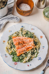 Plate with noodles, salmon and spinach on white rustic table background. Healthy food meal. Dieting. Lunch. Top view