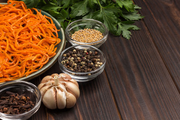 Fermented carrots in plate. Spices, garlic and parsley on table.
