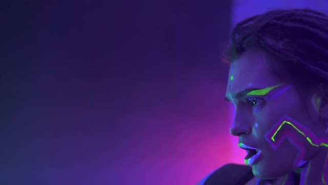 Portrait of a Girl with Dreadlocks in Neon UF Light. Model Girl with Fluorescent Creative Psychedelic MakeUp, Art Design of Female Disco Dancer Model in UV, Colorful Abstract Make-Up. Dancing Lady
