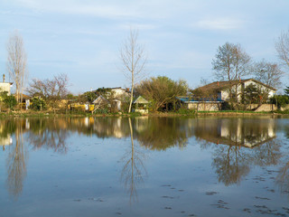 Obraz premium the houses near a lake with a green background. the blue reflected in the lake. 