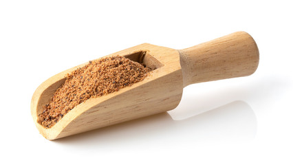 Nutmeg powder in wood scoop on white background