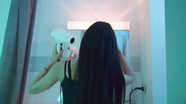 Femme se pr&eacute;pare dans salle de bain avec s&egrave;che cheveux