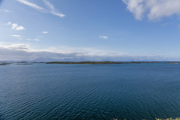 A mystical fjord in Norway with mountains and fog hanging over the water in polar day. midnight sun, selective focus