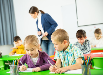 Portrait of schoolchildren sitting in classroom and chatting during lesson