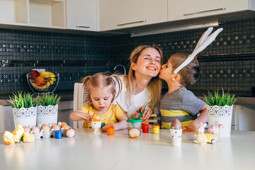 Happy easter! A mother and her daughter and son painting Easter eggs. Happy family preparing for...