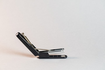 black stapler for fastening papers on a gray background