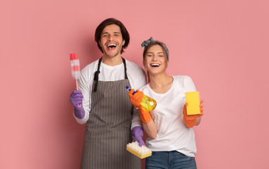 Cheerful Millennial Couple With Cleaning Supplies In Hands Over Pink Background