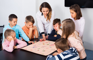Fototapeta premium Boys and little girls playing at board game