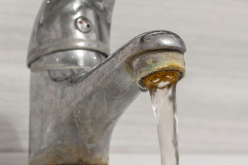 Old Bathroom Sink Faucet contaminated with calcium and grime. Hard water flows from an old tap...