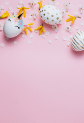 Easter eggs in the form of a unicorn and eaggs with gold pattern on pink background with flowers. Happy Easter time. Creative Easter decoration. Copy space. Flat lay