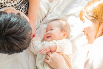 赤ちゃんを中心に寝転ぶ幸せそうな父と母