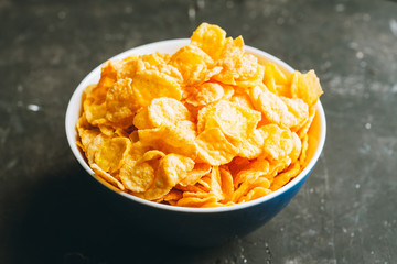 Tasty crispy corn flakes in bowl on the rustic background. Selective focus. Shallow depth of field.
