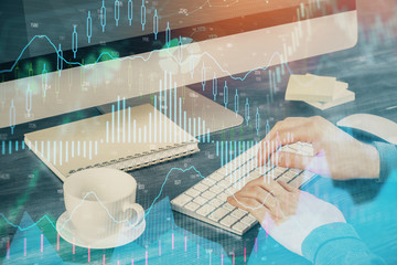 Multi exposure of graph with man typing on computer in office on background. Concept of hard work.