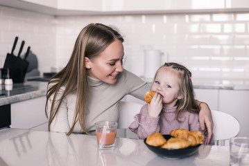 Young mother and daughter having breakfast at kitchen table