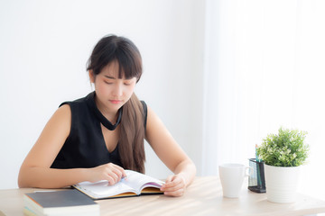 Beautiful young asian woman smiling sitting study and learning writing notebook and diary in the living room at home, girl homework, business woman working on table, education concept.