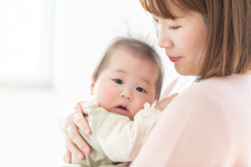 明るい部屋の中で赤ちゃんを抱っこするお母さん