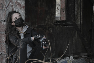 Teenager girl in a black medical mask, on the background of an abandoned building. Consequences of COVID-19 Coronavirus protection. After a pandemic