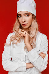 Close up portrait of a female doctor in white medical coat and protective face mask, isolated on a red background. Professional healthcare people and medicine concept