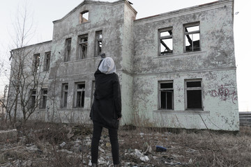 The figure of a teenager girl looking at an abandoned destroyed building. Consequences of COVID-19 Coronavirus protection. After a pandemic