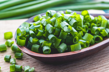 Fresh green onion chopped and lies on a bowl on a chopping board on a background of blue boards.