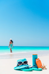 Fototapeta na wymiar Suncream bottles, goggles, starfish and sunglasses on white sand beach background ocean