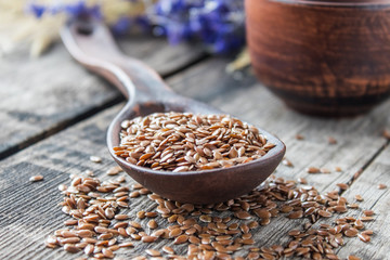 Flax seeds lie on old boards and in a spoon on a wooden table.