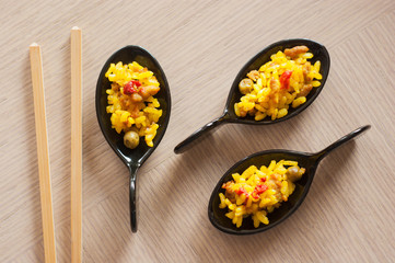 Rice tapa with meat, green peas and pepper served in black spoons