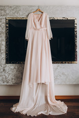 pink evening dress hanging on the wall in the room. Wedding Dress