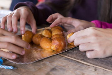 Hands of young people sharing fritters with cream