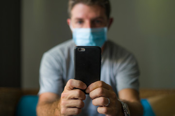 following online news on covid-19 virus pandemic - man with face mask in home quarantine lockdown...